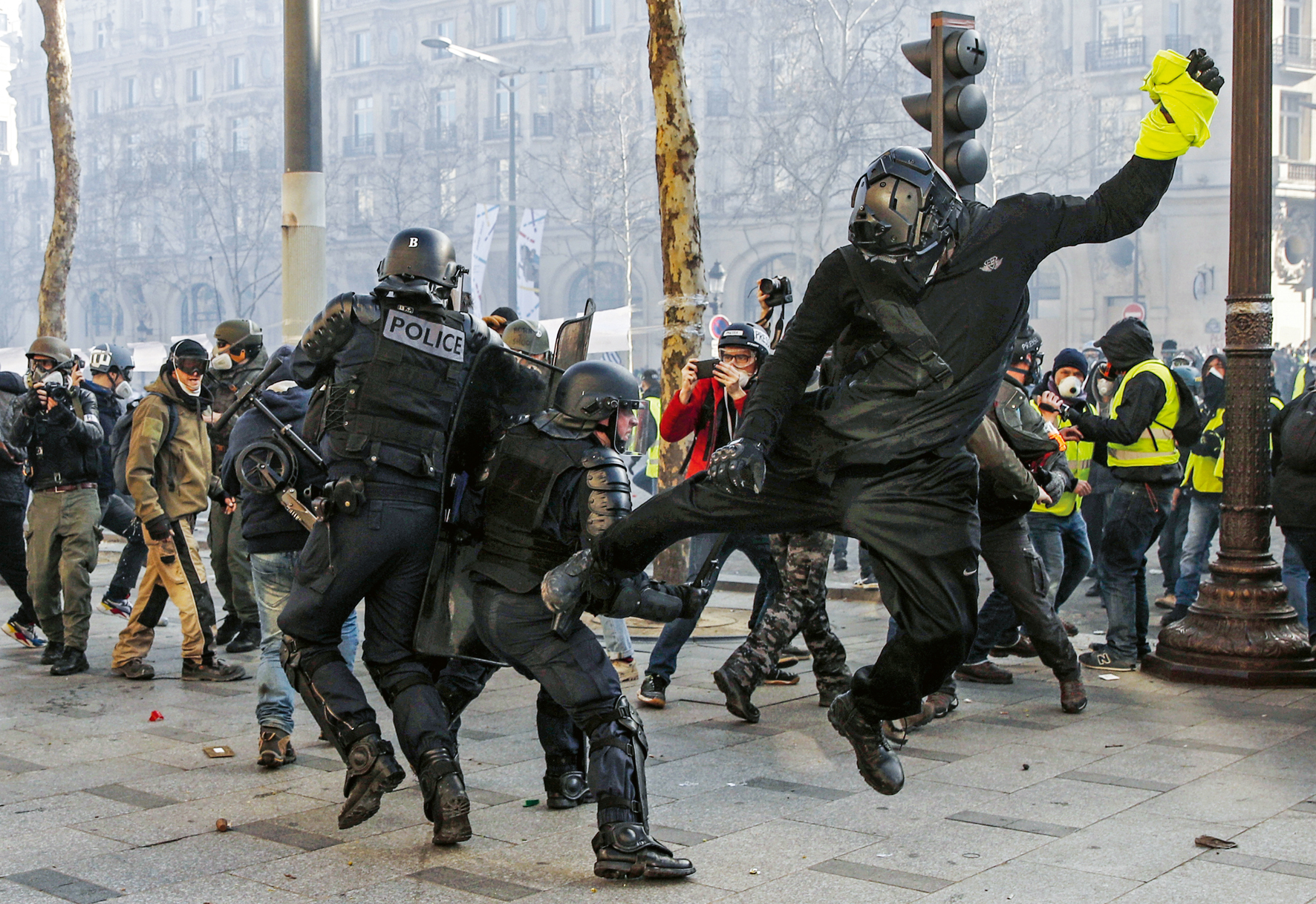 epaselect epa07442881 A Yellow Vest protester hits a riot police officer with his leg on the Champs Elysees during the 'Act XVIII' demonstration (the 18th consecutive national protest on a Saturday) in Paris, France, 16 March 2019. The so-called 'gilets jaunes' (yellow vests) is a grassroots protest movement with supporters from a wide span of the political spectrum, that originally started with protest across the nation in late 2018 against high fuel prices. The movement in the meantime also protests the French government's tax reforms, the increasing costs of living and some even call for the resignation of French President Emmanuel Macron. EPA-EFE/YOAN VALAT